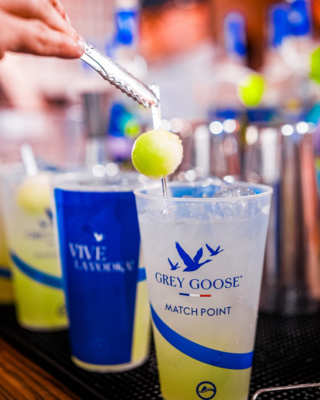 drinks com vodka fáceis em copo transparente com logo azul da Grey Goose, gelo e decoração delicada sobre mesa de madeira