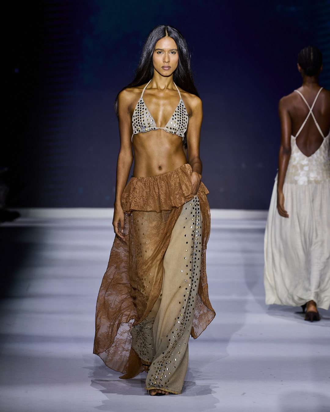 Modelo usando top de biquíni com tachas prateadas e saia de renda marrom tendências de moda 2026