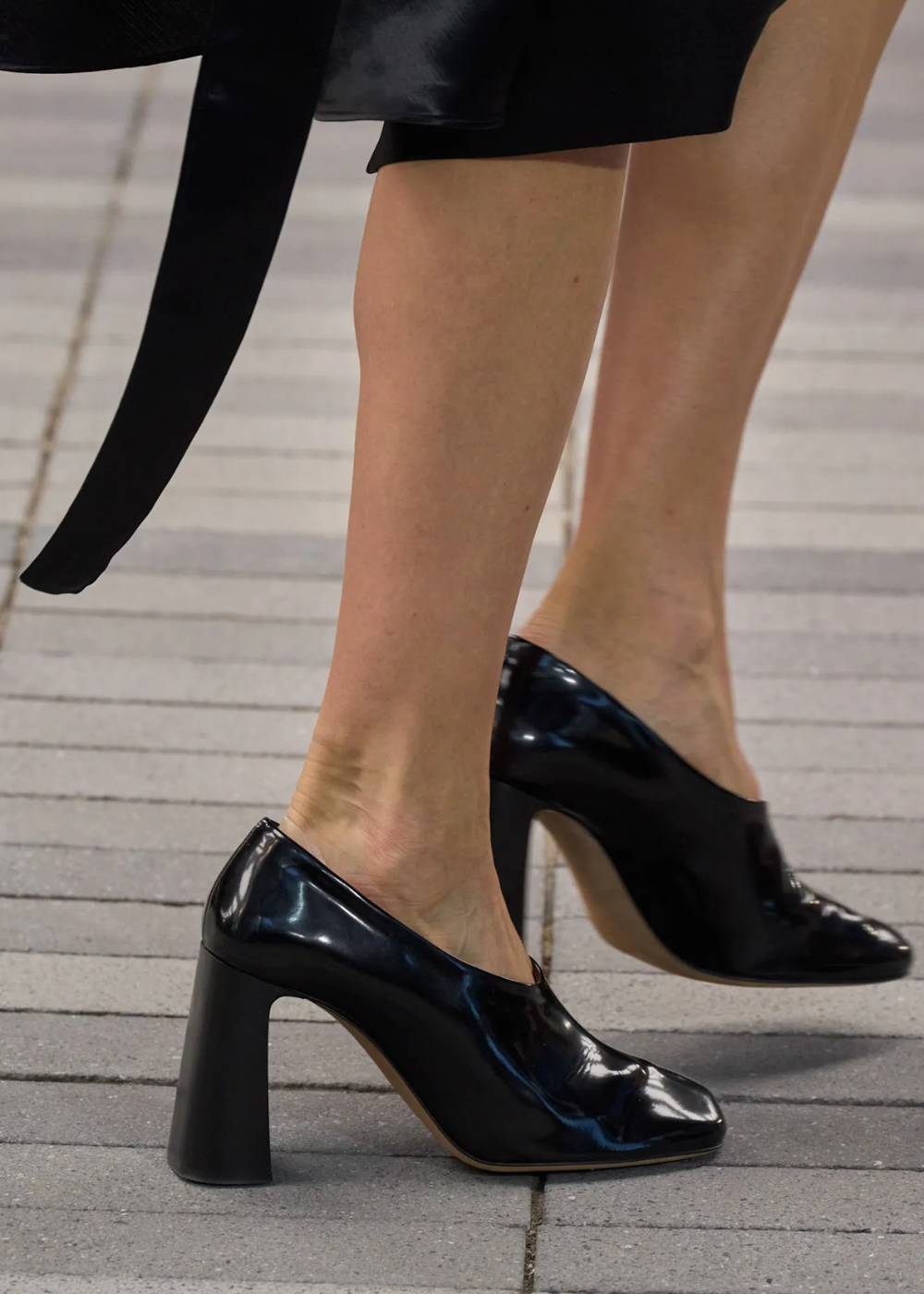 Vamp pumps em couro preto brilhante com salto bloco alto e bico arredondado, combinando elegância e modernidade urbana.
