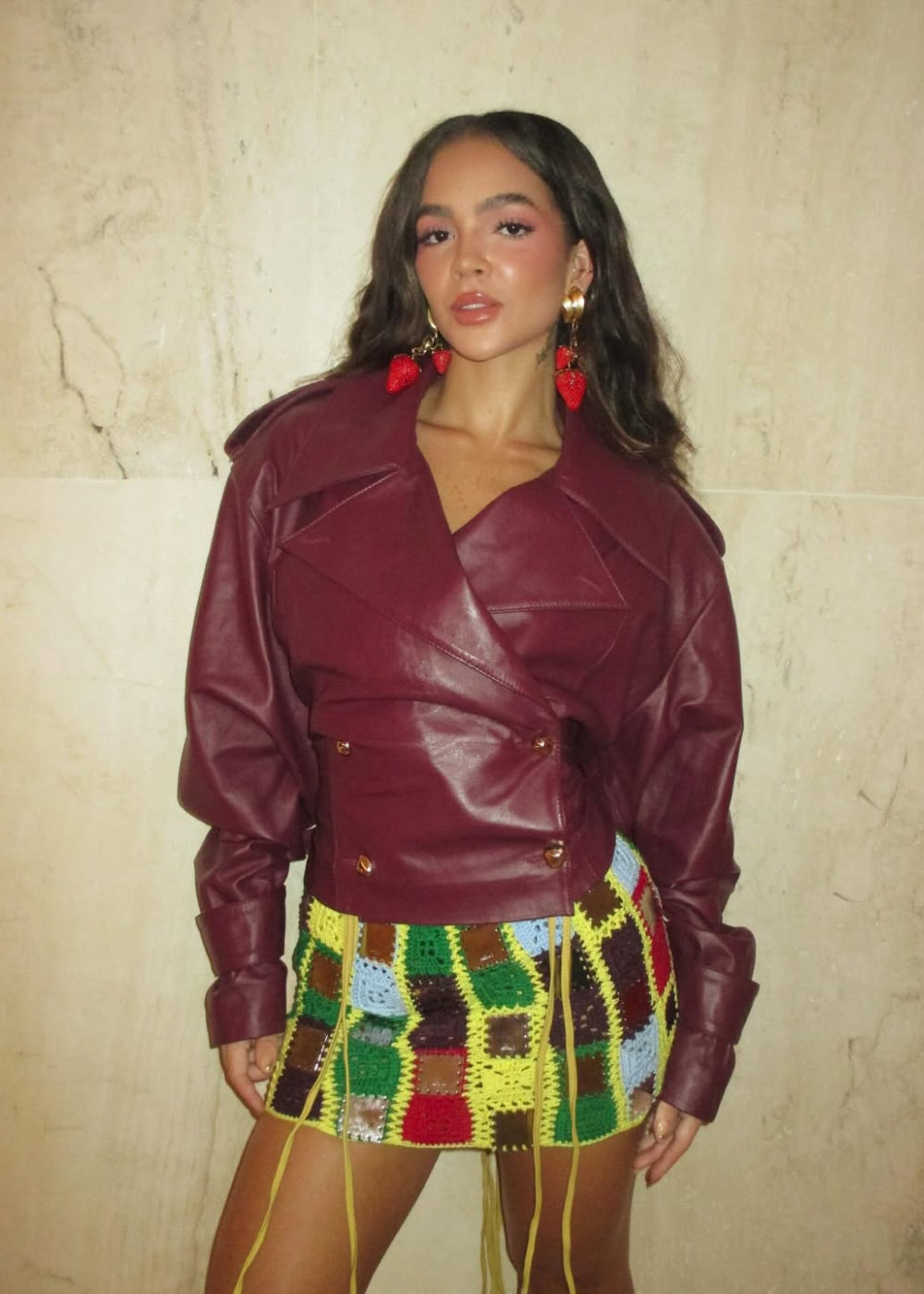 No desfile da MISCI na Sapucaí, modelo posa com jaqueta vinho e minissaia de crochê colorida em clima marcante.