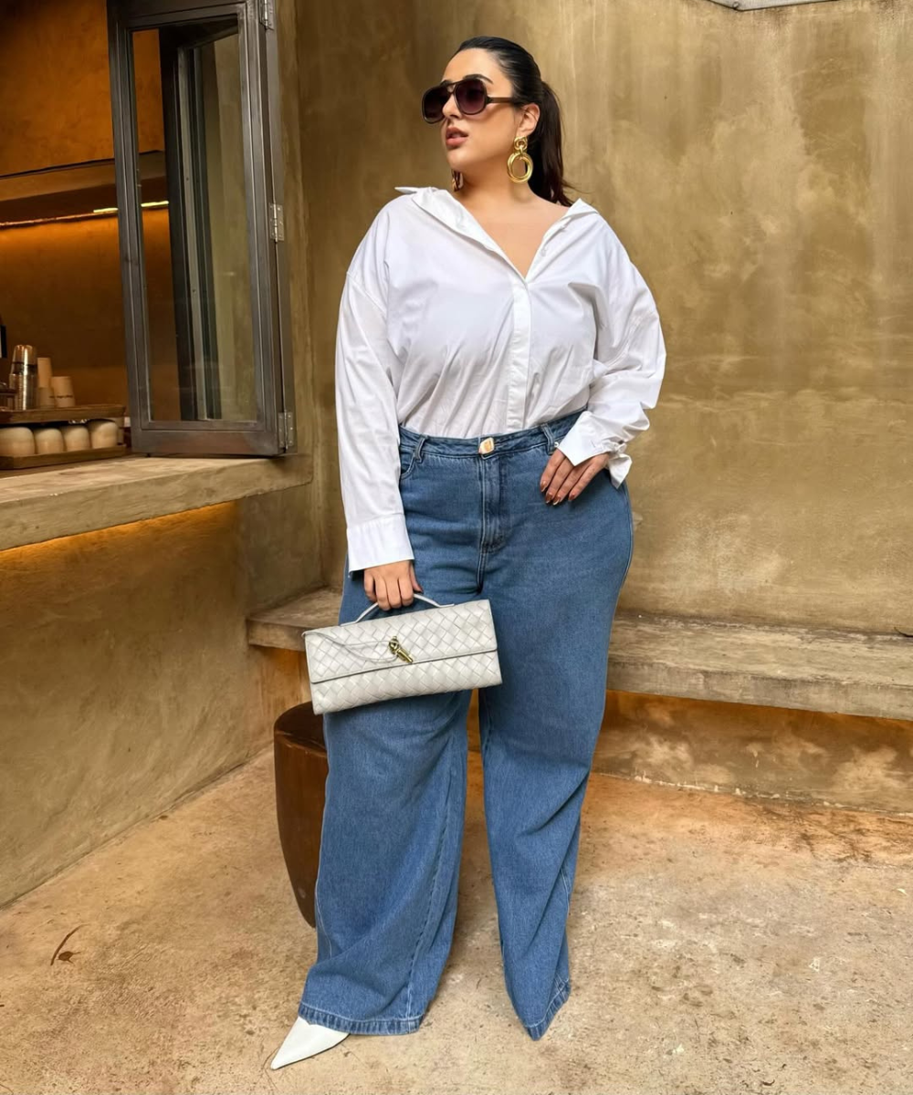 Looks com scarpin branco elevam camisa ampla e jeans wide leg azul; modelo posa com bolsa matelassê em clima elegante.