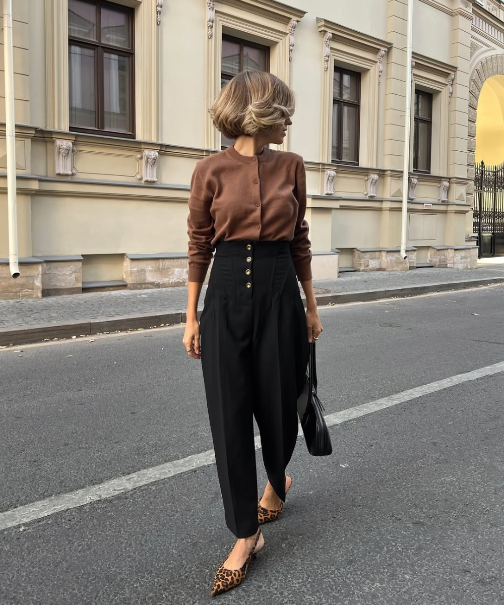 Looks com scarpin: modelo posa com cardigan marrom, calça preta de cintura alta e scarpin animal print elegante.
