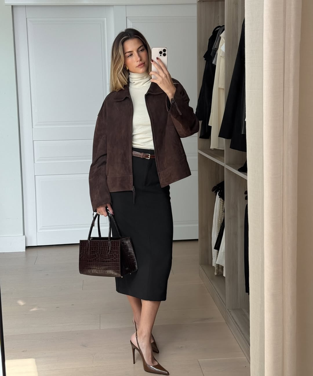 Looks com scarpin: modelo posa no espelho com jaqueta marrom, gola alta off-white, saia preta midi e bolsa croco elegante.