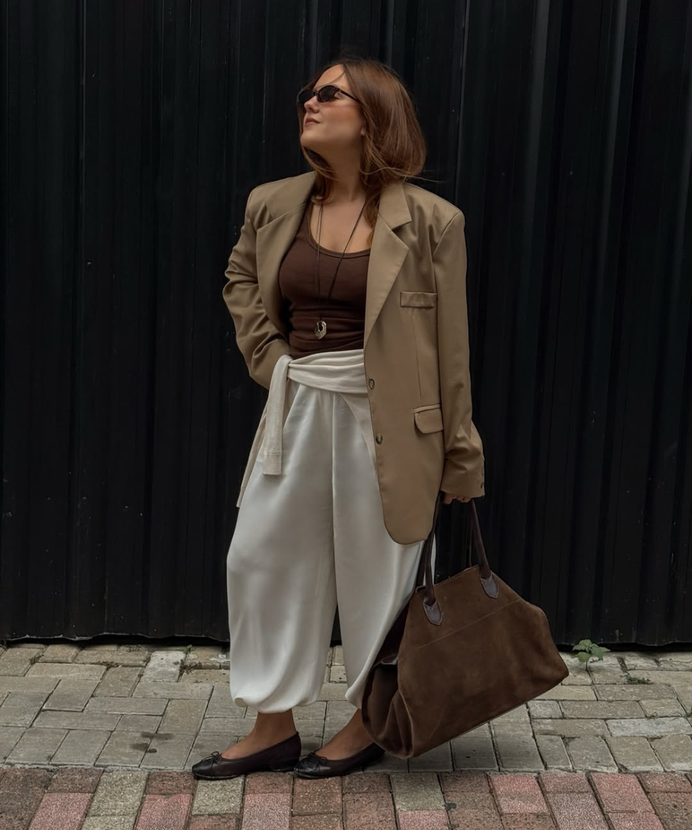 Looks com calça de moletom: modelo posa com blazer bege, regata marrom e calça branca ampla em clima elegante.