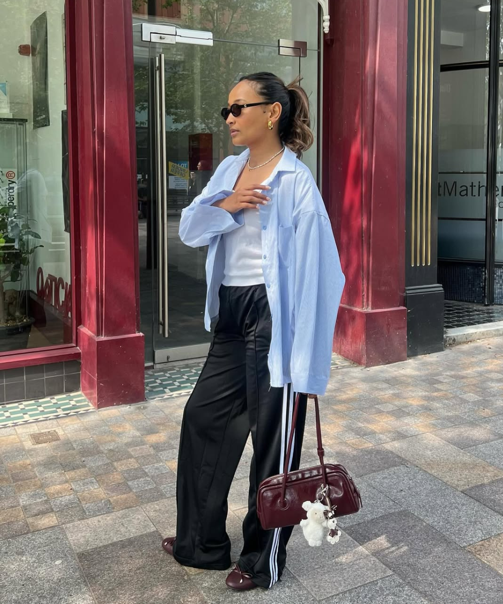 Looks com calça de moletom preta e listras, camisa azul ampla e regata branca criam visual urbano elegante.