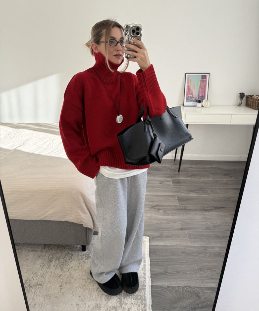 Looks com calça de moletom cinza: modelo posa com tricô vermelho oversized, bolsa preta e clima casual elegante.