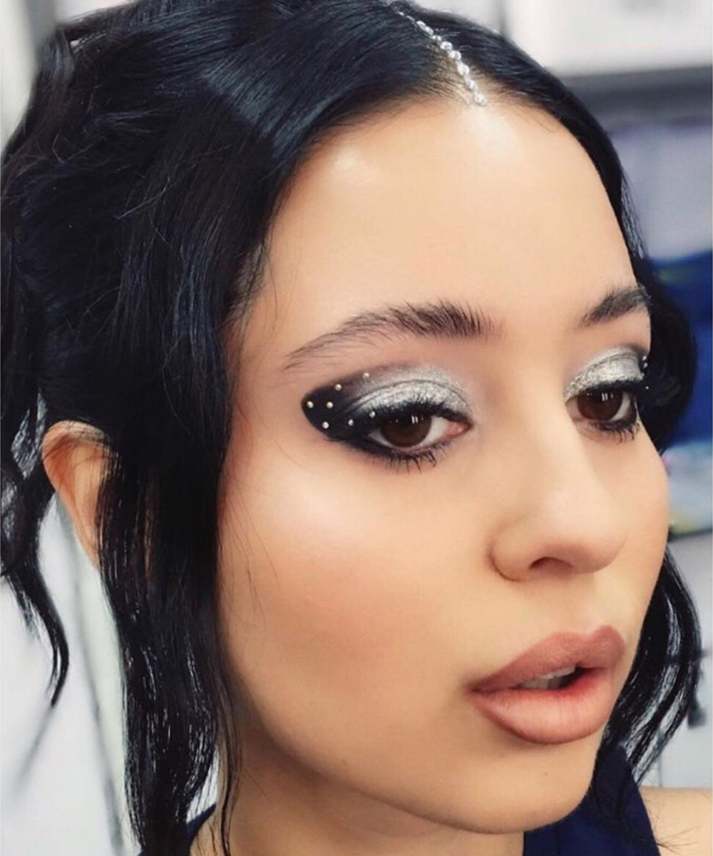 Maquiagens de euphoria com sombra prata, delineado preto e strass; modelo posa com coque e clima futurista