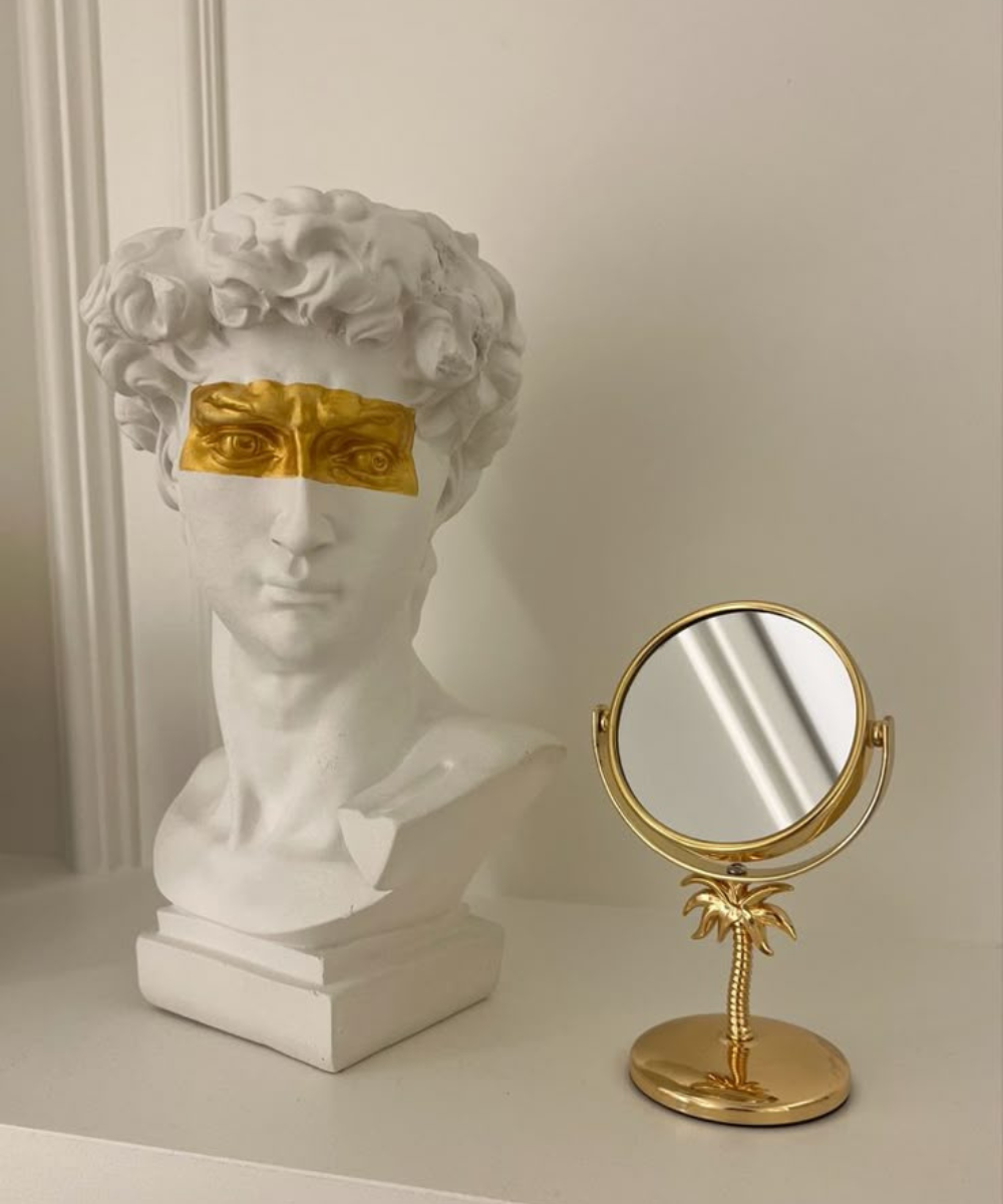 Protocolo de beleza em cena clean com busto branco, máscara dourada nos olhos e espelho dourado, clima sofisticado.