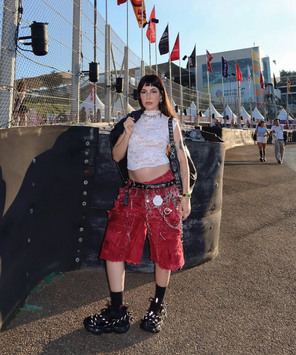 Looks de grávidas inspiram visual urbano: modelo posa com top rendado branco, bermuda vermelha e correntes em clima ousado.