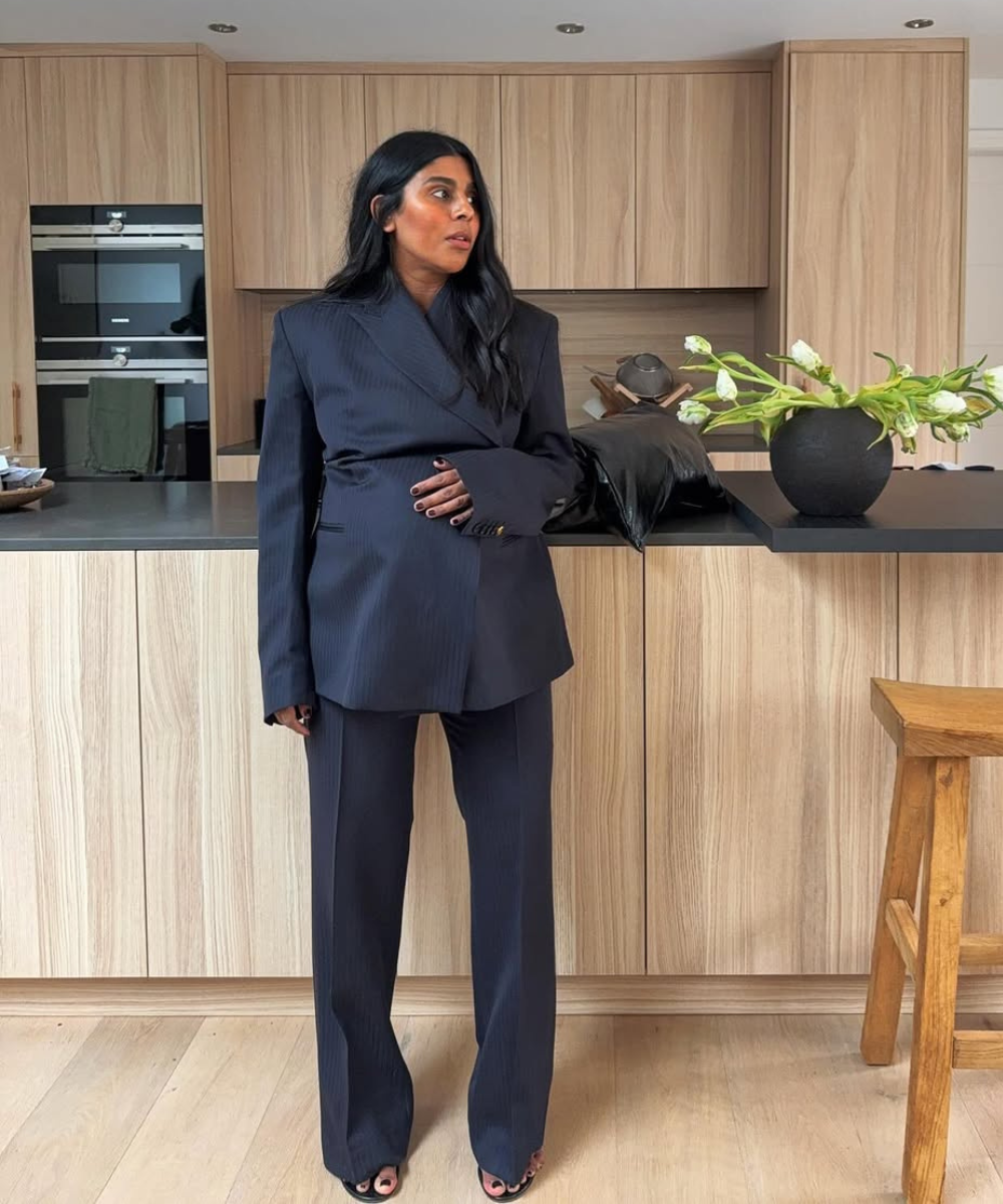 Looks de trabalho para usar durante a gravidez com blazer amplo e calça reta azul-marinho em cozinha elegante, modelo posa