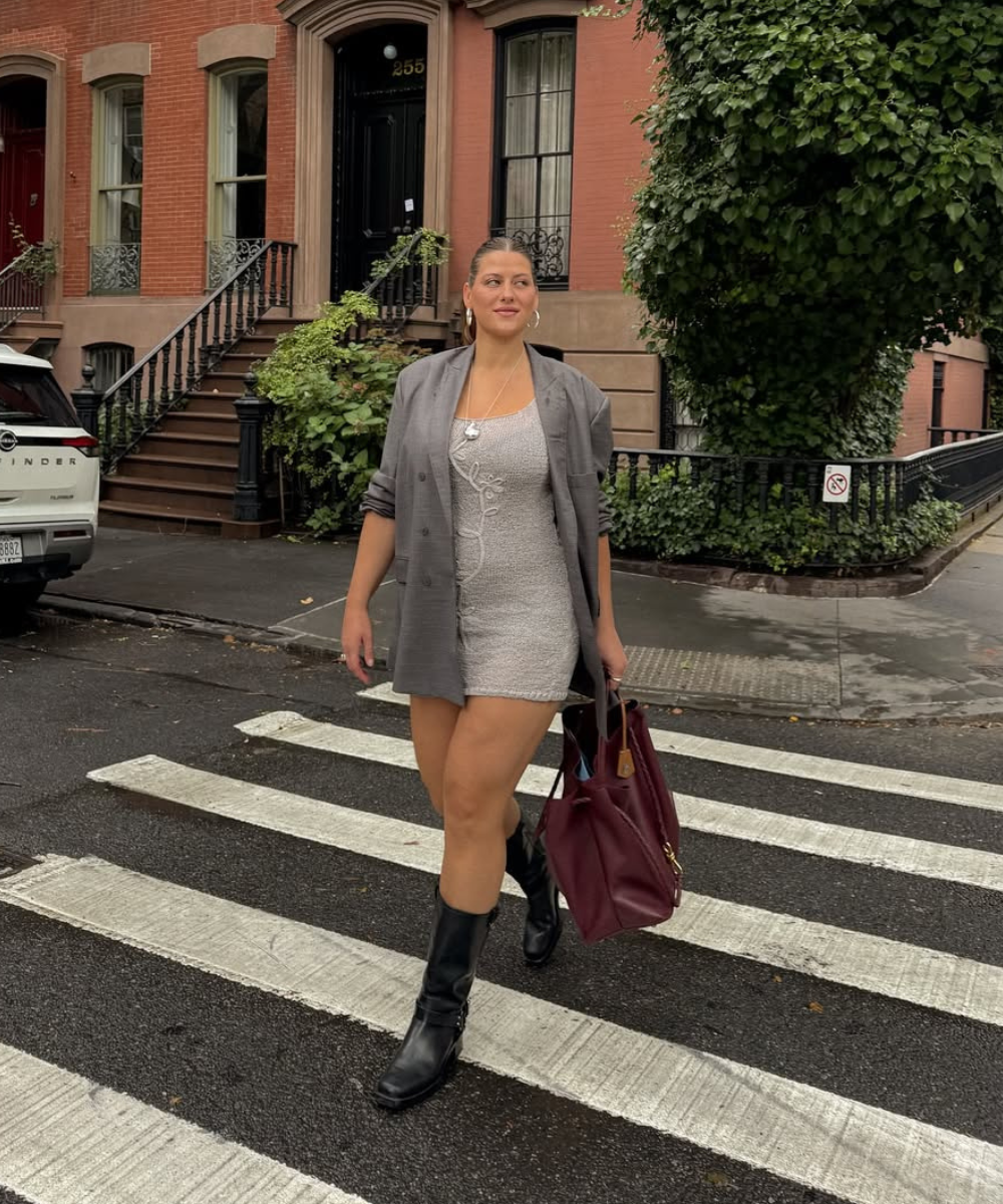 Modelo cruza a rua com blazer cinza, vestido curto e bolsa vinho, uma das cores de bolsa mais chiques para o outono.