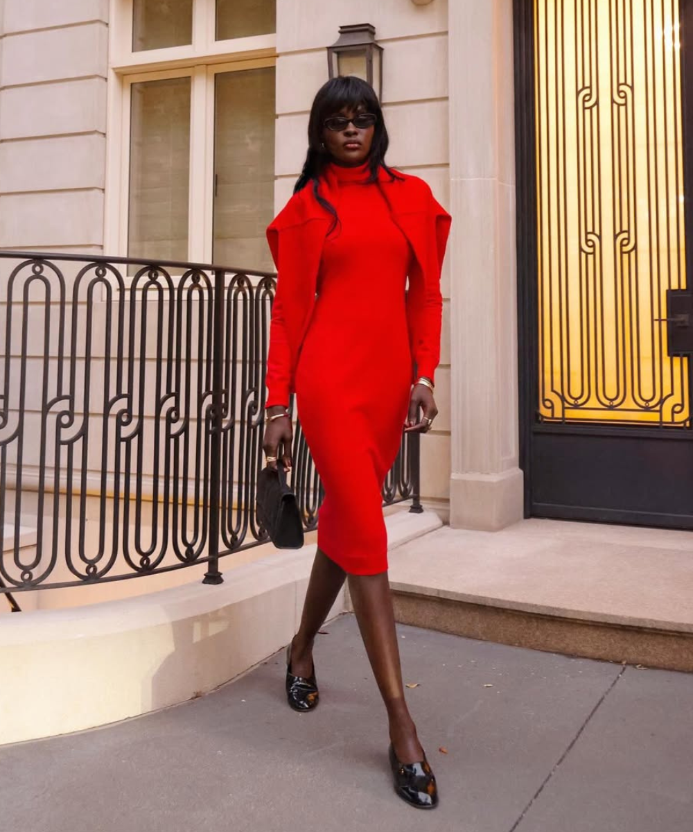 Modelo posa em vestido vermelho ajustado com bolsa preta, uma das cores de bolsa mais chiques para o outono.