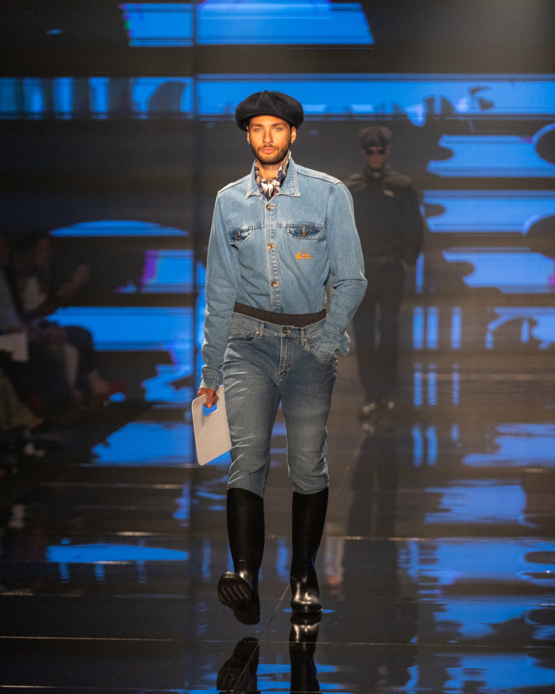 Modelo desfila com denim azul total e boina preta, look utilitário entre cores e estampas tendência do outono inverno 2026.