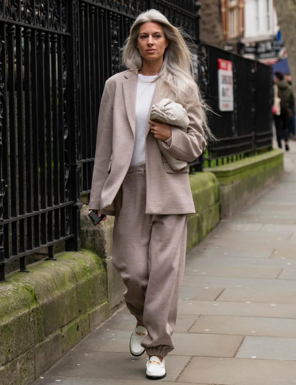 Mocassins femininos estilosos em branco com metal dourado; modelo caminha de alfaiataria bege com elegância urbana.