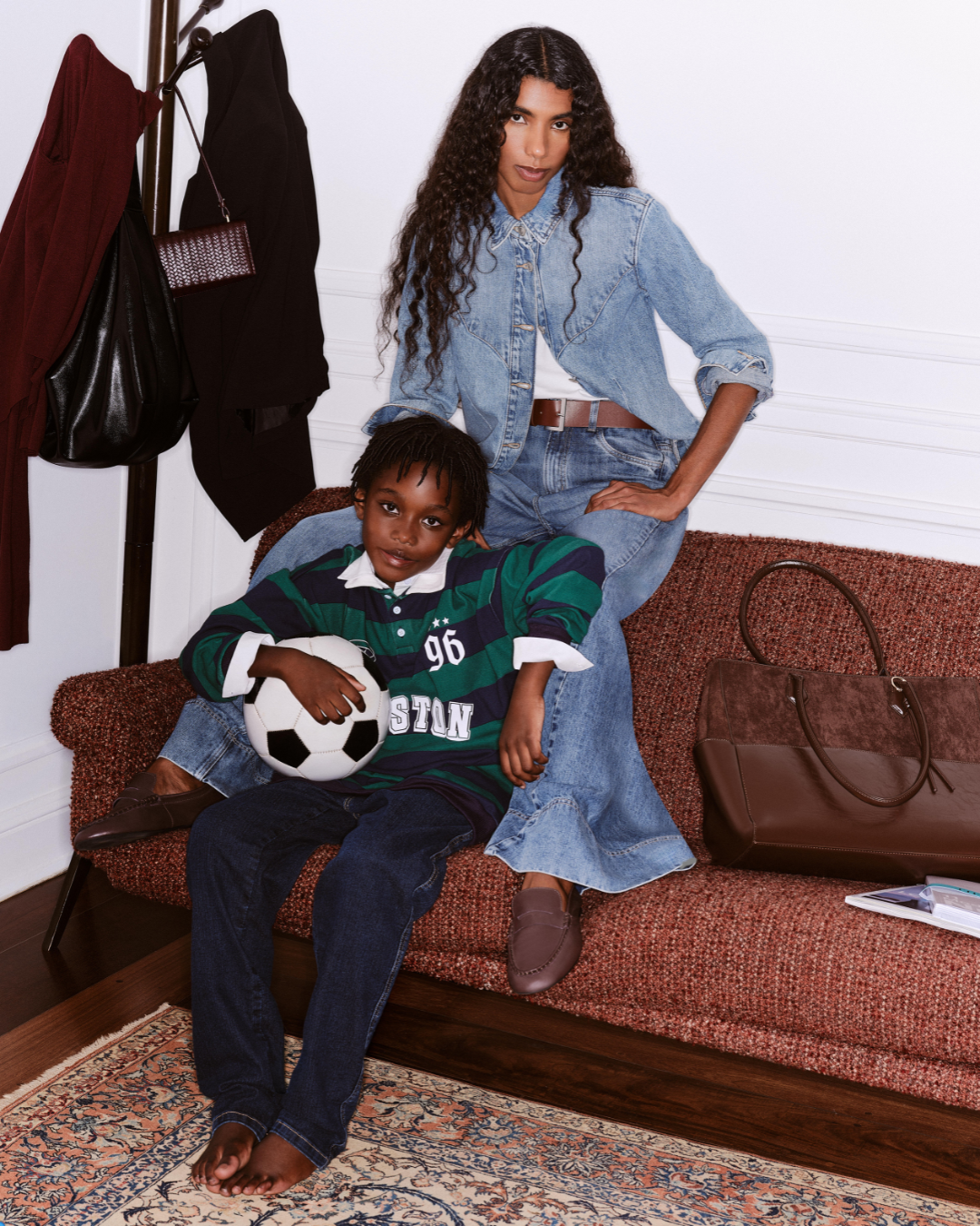 Moda e maternidade em cena: modelo posa com jeans amplo; criança com bola usa polo listrada verde e azul.