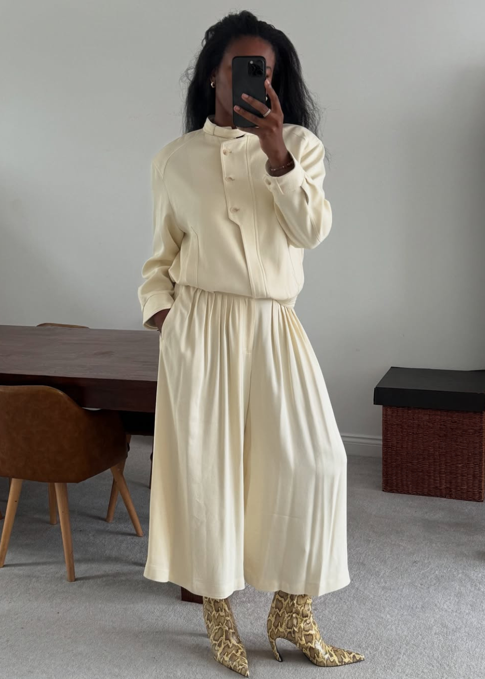 Modelo posa com conjunto creme fluido e sapatos arquitetônicos de cobra, em clima elegante e contemporâneo.