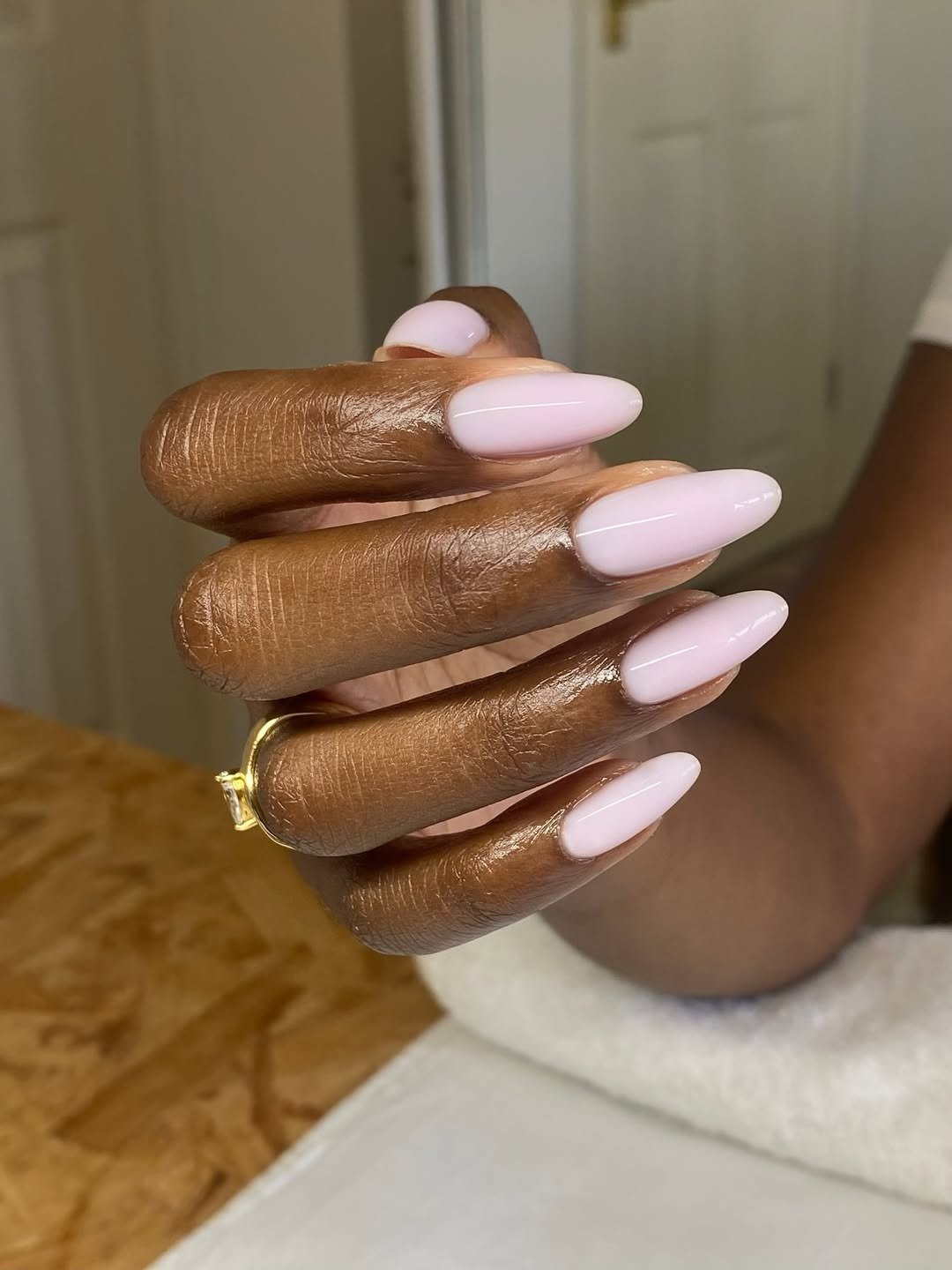 Unhas para madrinha de casamento em formato amendoado, rosa leitoso brilhante e anel dourado criam visual elegante.