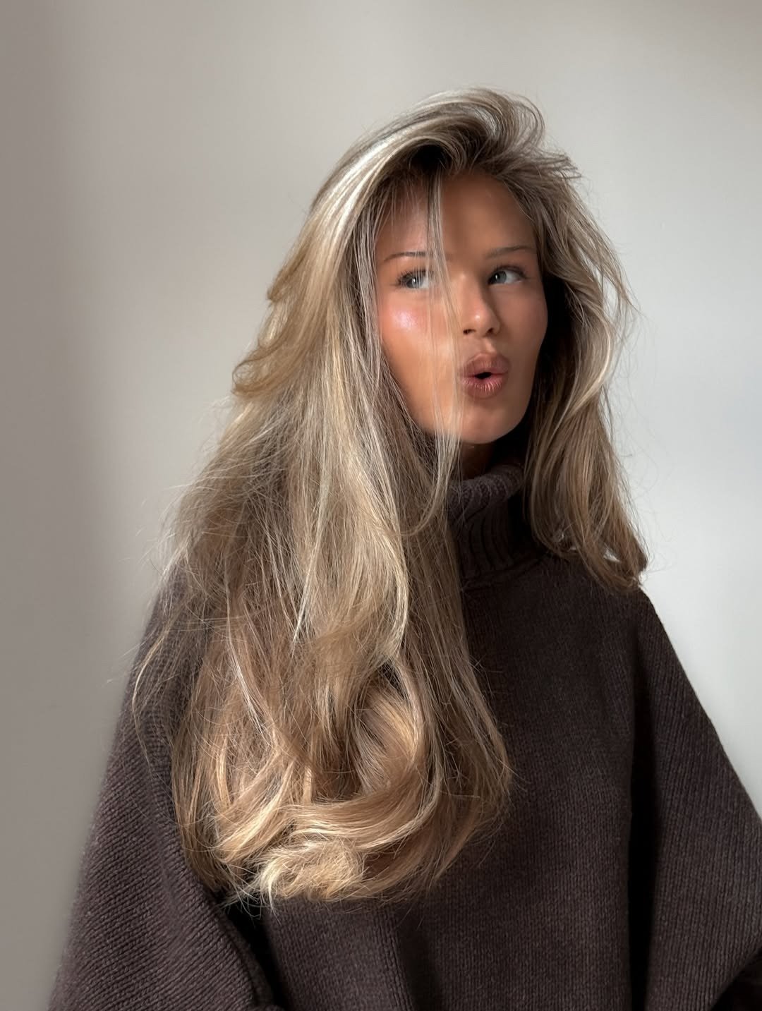 Melhores kits de shampoo destacam modelo de suéter marrom com cabelo loiro volumoso e brilho suave em clima elegante