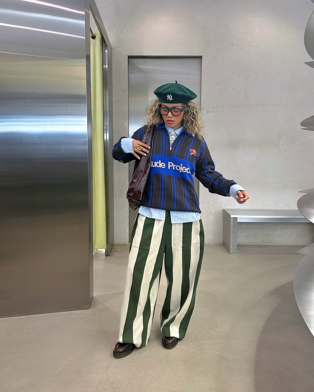 Looks estilosos para a variação de temperatura no outono com sobreposição listrada azul e verde; modelo posa moderna.