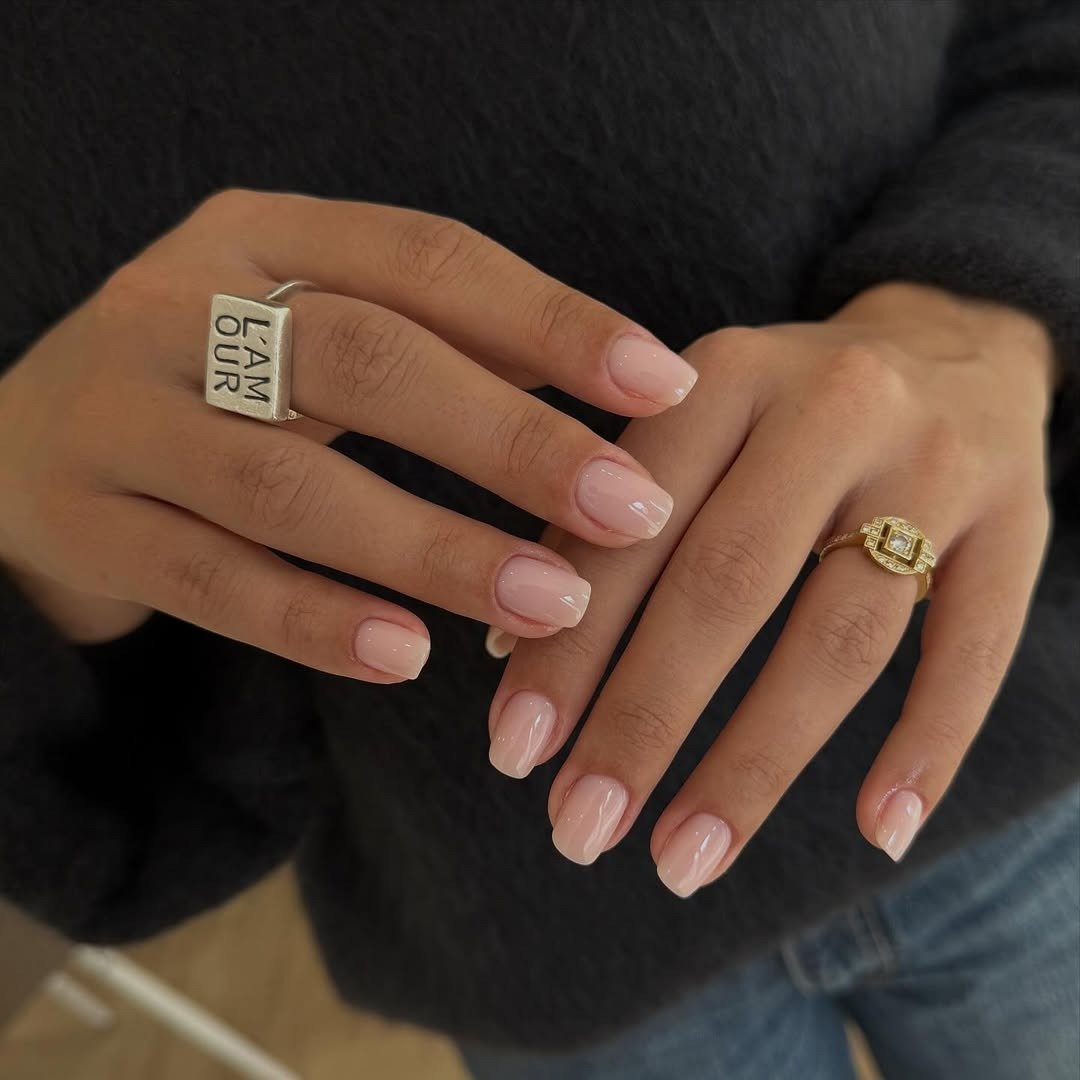 Unhas para madrinha de casamento em rosa leitoso brilhante e formato curto oval, com anéis dourado e prata.