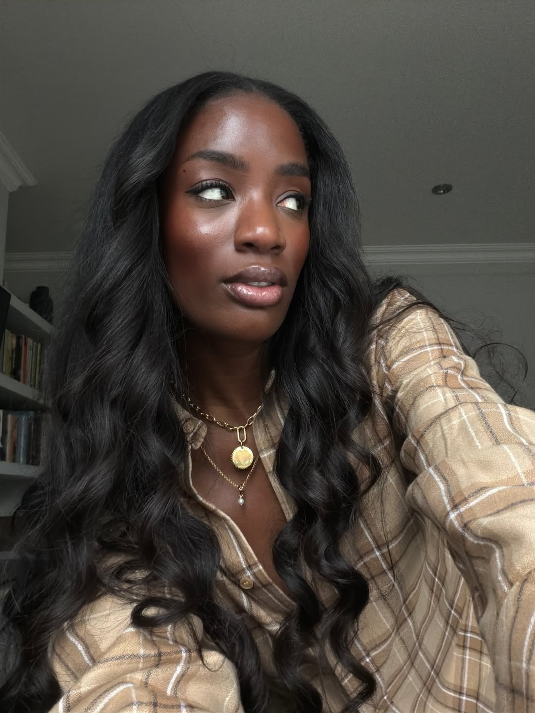 Melhores kits de shampoo destacam cabelo longo ondulado e brilhante; modelo posa de perfil com camisa xadrez bege em clima