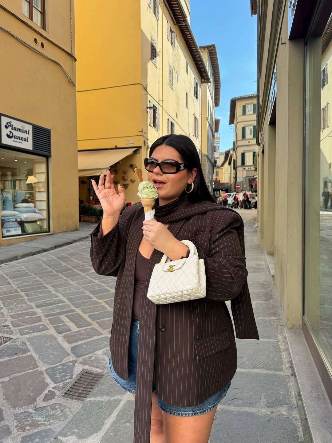 Looks estilosos para a variação de temperatura no outono: modelo posa de blazer risca de giz marrom e jeans.