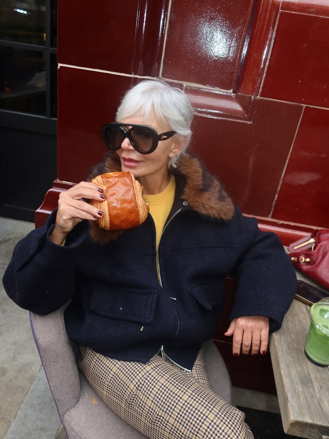 Melhor shampoo para cabelos grisalhos inspira modelo sentada com jaqueta de lã, gola de pele e clima sofisticado.