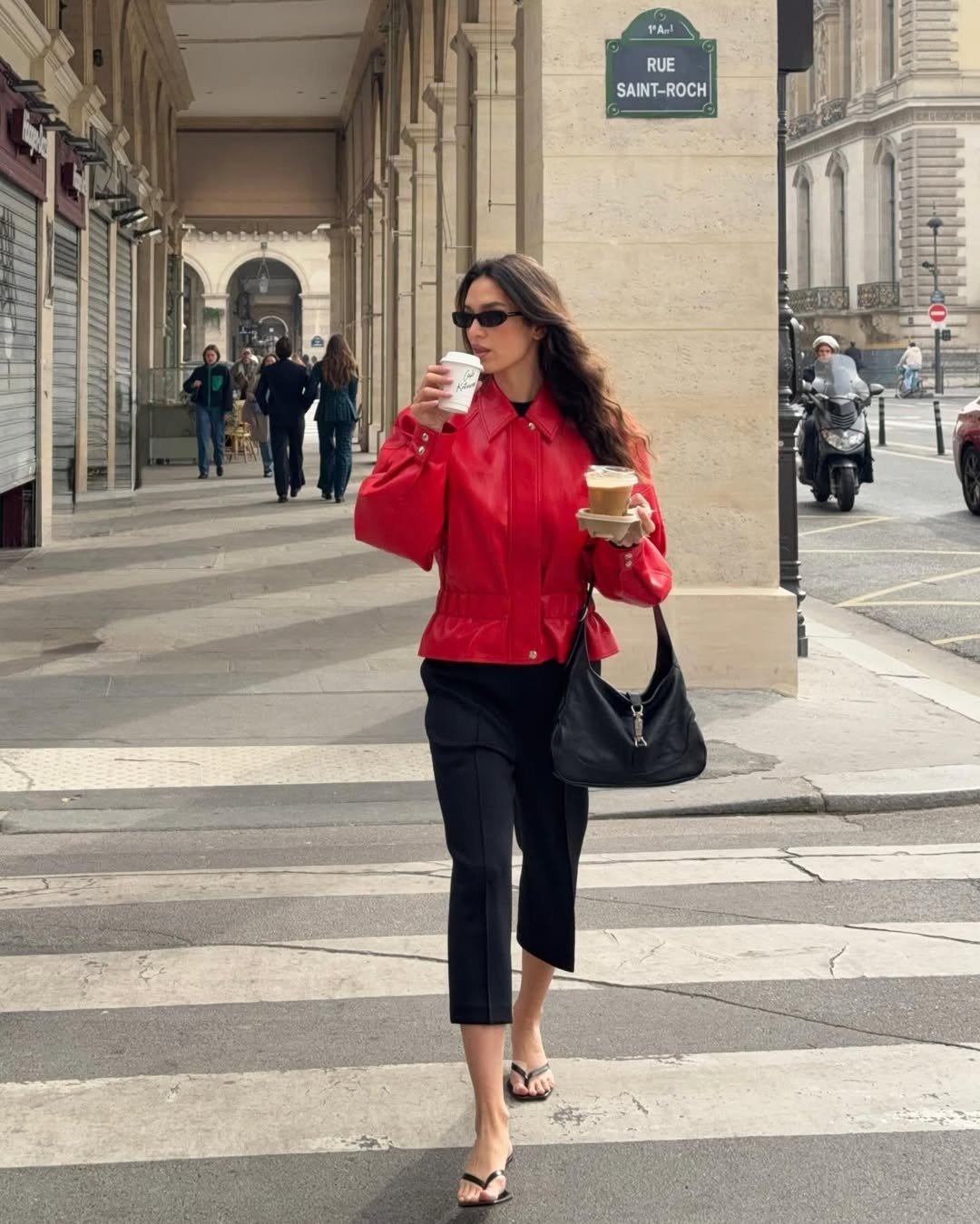 Modelos de calças de alfaiataria: modelo posa com corte reto preto, jaqueta vermelha e elegância urbana.