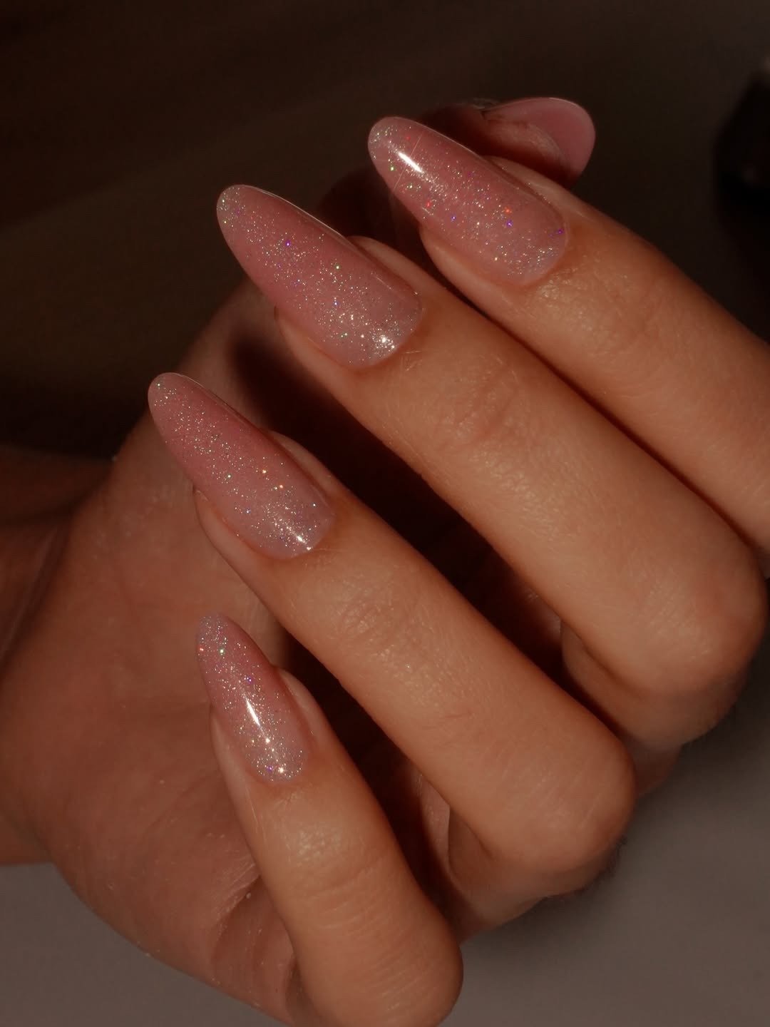 Unhas para madrinha de casamento em formato amendoado, rosa translúcido com glitter fino e brilho delicado elegante