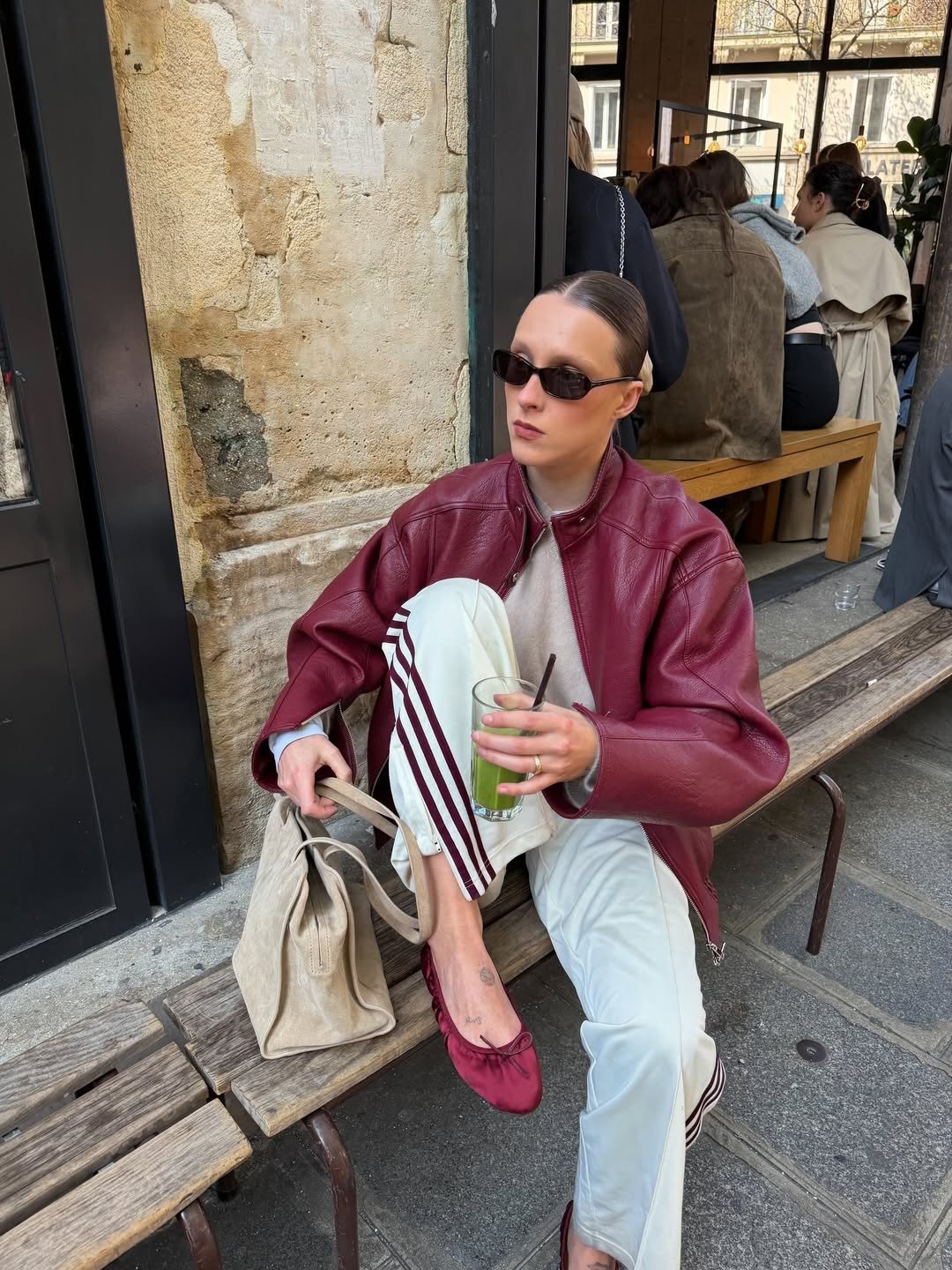 Looks estilosos para a variação de temperatura no outono: modelo posa com jaqueta vinho, calça off-white e clima urbano