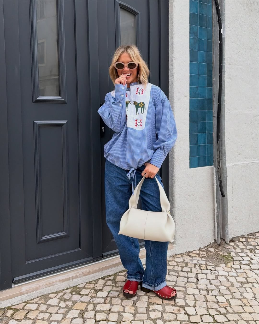 Looks estilosos para a variação de temperatura no outono com bata azul bordada, jeans amplo e bolsa off-white descontraída