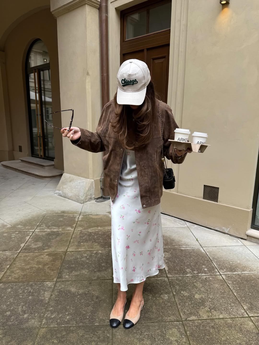 Looks estilosos de outono: modelo posa com jaqueta marrom e vestido floral.