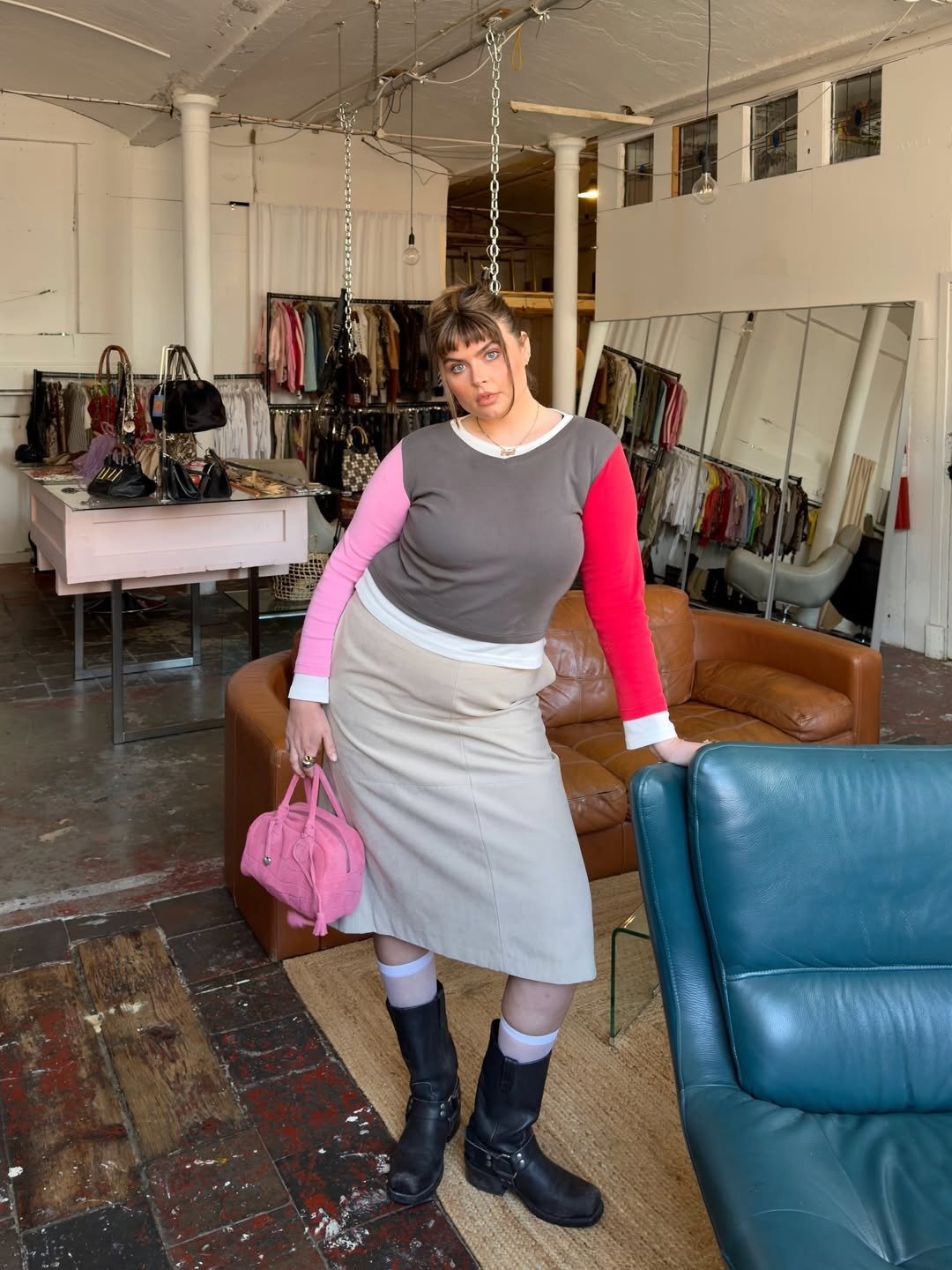 Melhores sapatos para o outono: modelo posa de botas pretas com saia midi bege e malha color block em brechó acolhedor