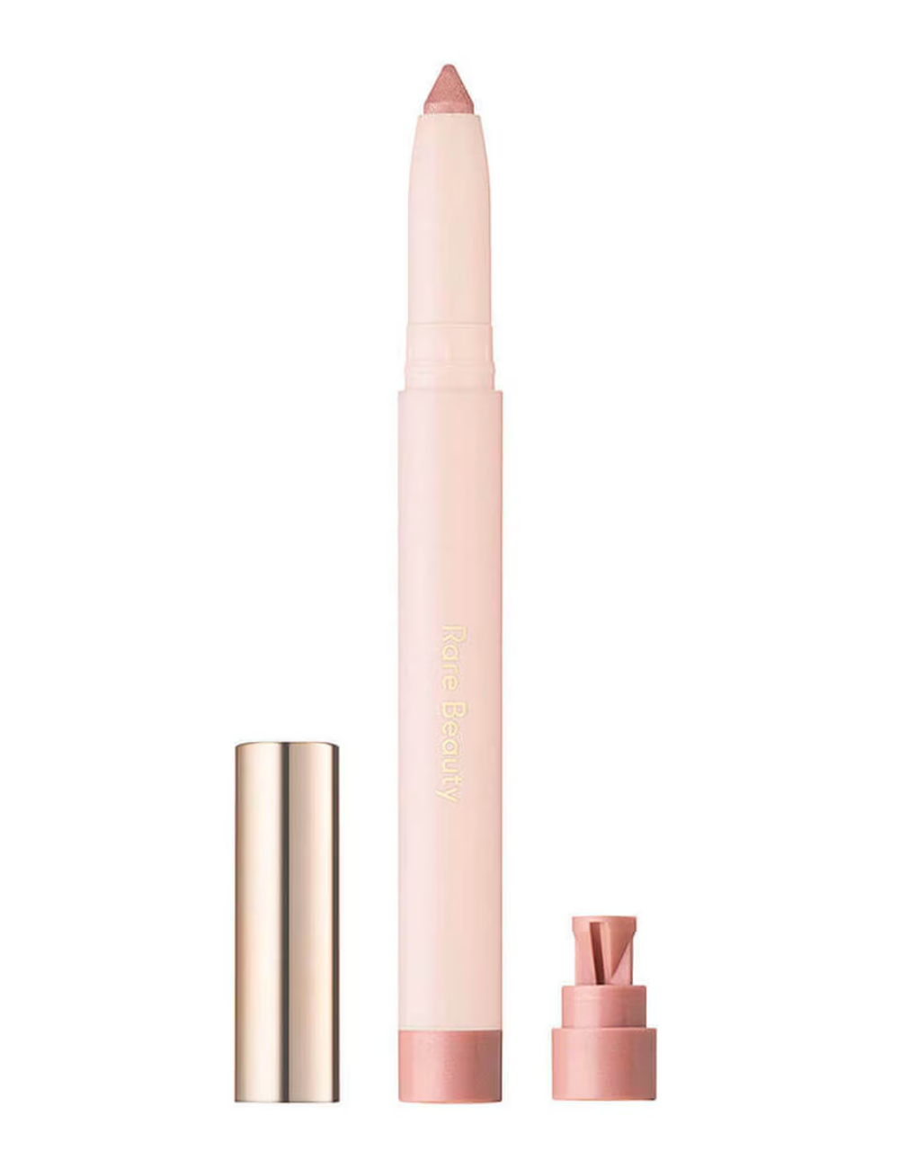 Sombras em stick Rare Beauty rosa cintilante com tampa dourada e design retrátil em fundo branco clean.