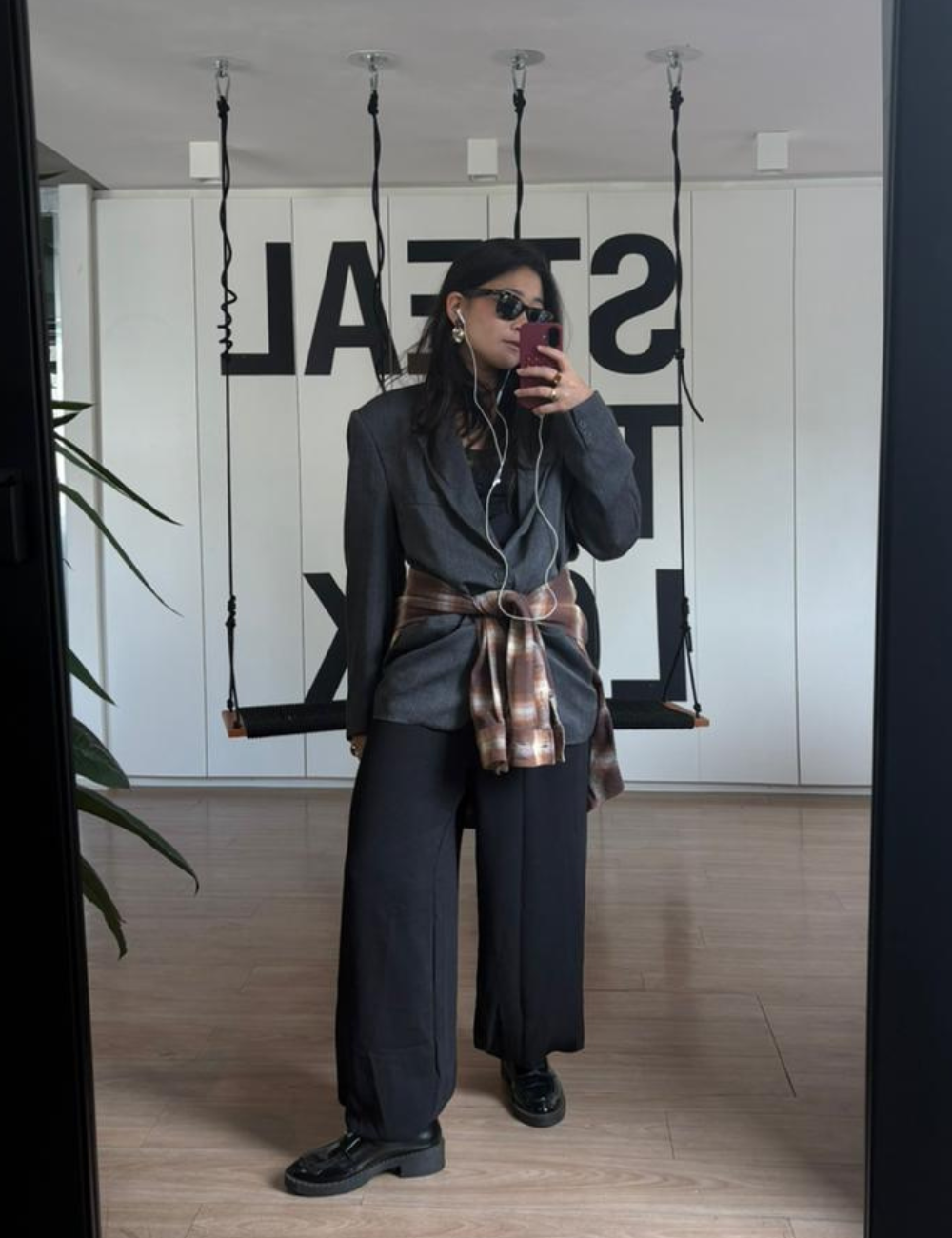 Tendência clássica: modelo posa de blazer cinza e calça ampla preta com camisa xadrez na cintura; Texto: STEAL THE LOOK