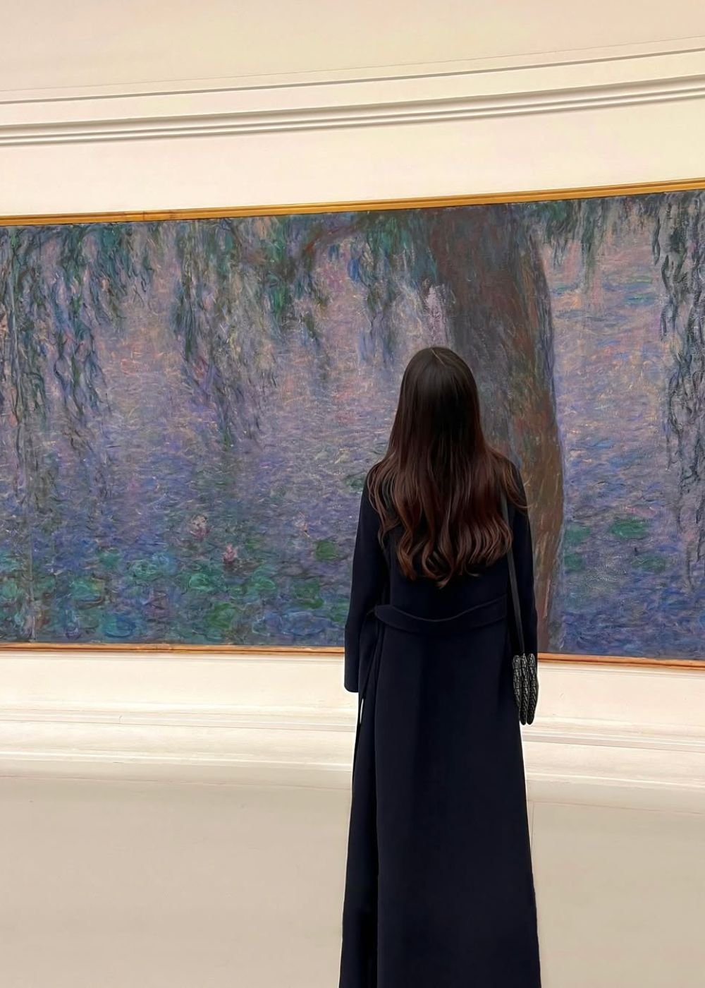 Mulher posa de costas com casaco longo preto diante de obra em lilás e azul, clima sofisticado e contemplativo.