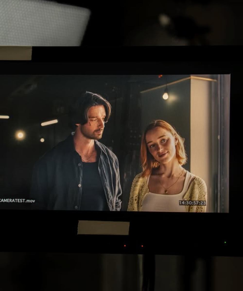 Livros que vão virar adaptações para a televisão em monitor com casal posa em look casual e luz quente.