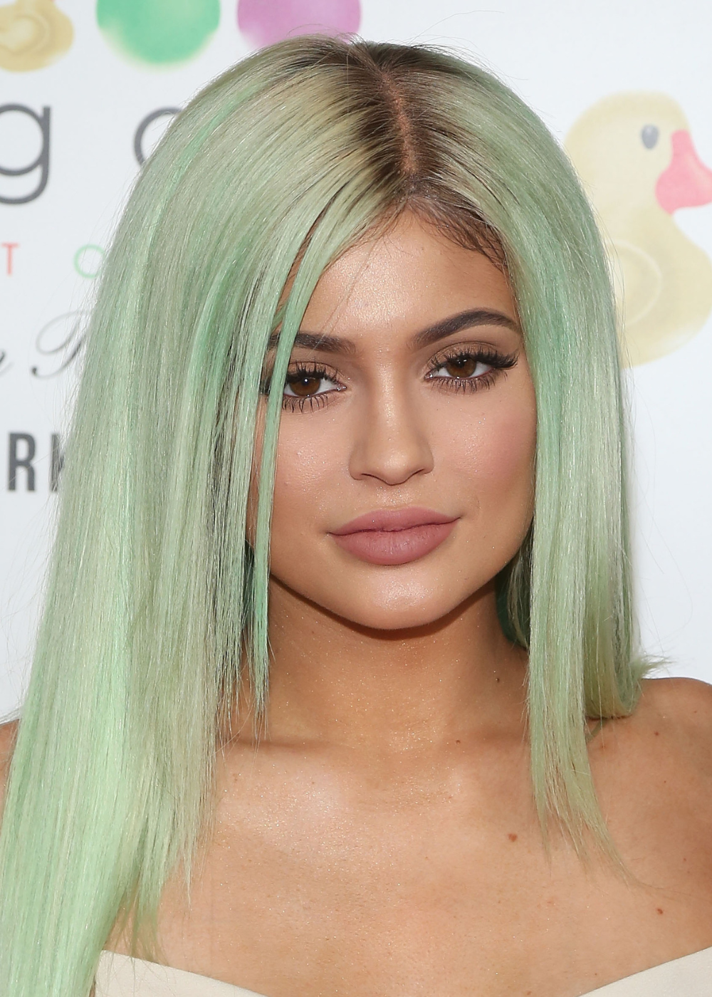 Modelo posa com cabelo verde-menta liso e maquiagem dos anos 2010 de boca nude e delineado marcante, em clima glamouroso.